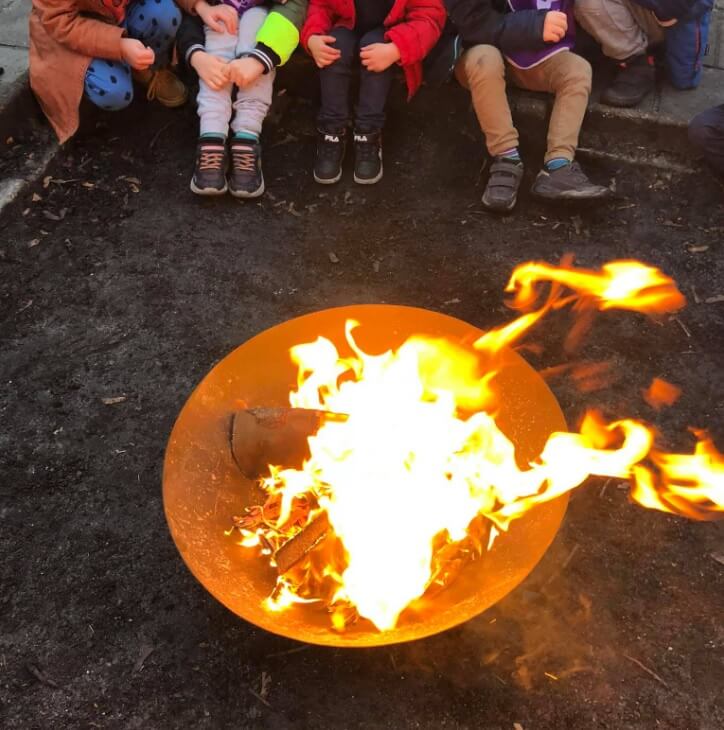 Kinderen zitten bij het kampvuur bij Zo Outdoor BSO in de Duinpan