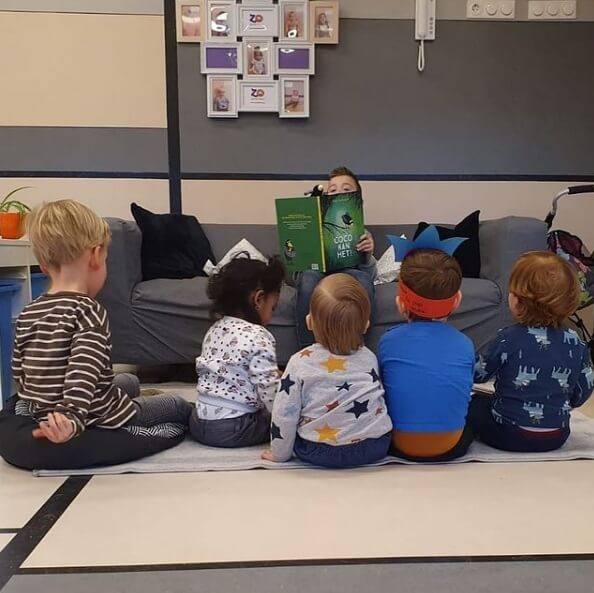 Een kind leest de andere kinderen voor op de dagopvang