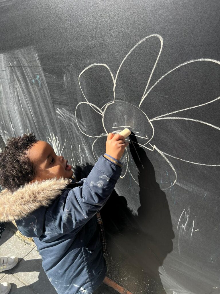 Kind is aan het tekenen met krijt bij Zo aan de Palmyraplaats