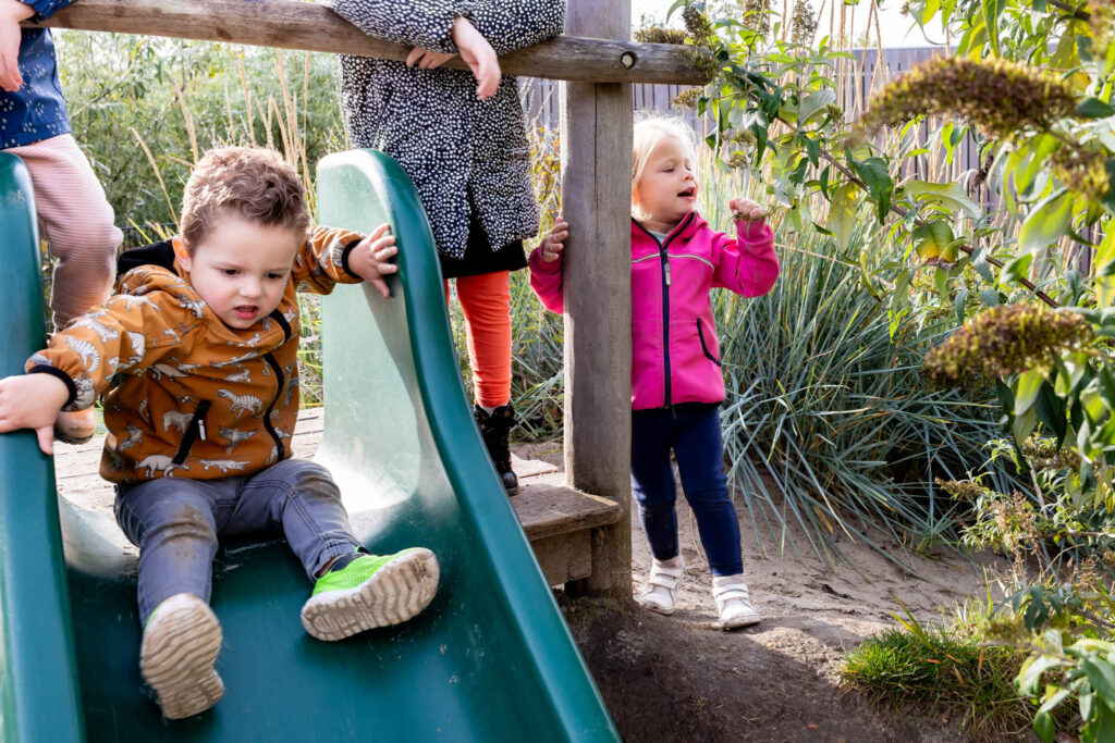 Peuters spelen buiten op de glijbaan op de peuteropvang