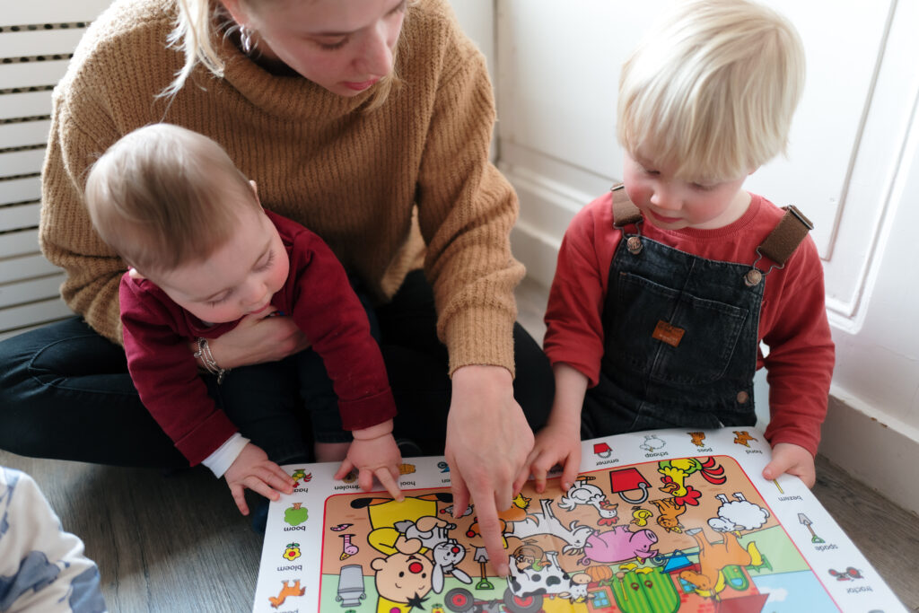 Pedagogisch medewerker en kinderen lezen samen in een boekje