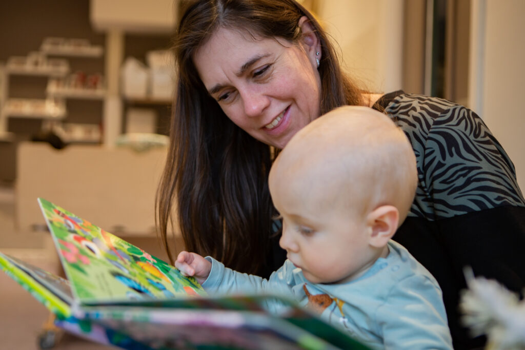 Pedagogisch medewerker en kind lezen samen in een prentboekje