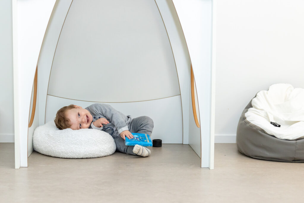 Kind ligt op een kussen met een boekje en lacht